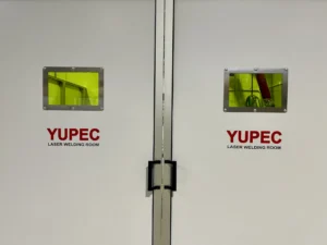 Foto primo piano della porta chiusa della cabina di saldatura realizzata da Yupec Service Italia, posizionata in azienda con vista da tre quarti