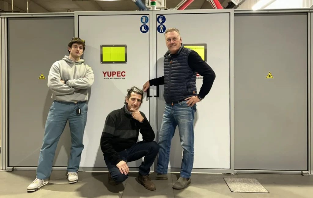 Foto dei 3 soci di Yupec Service Italia, in posa di fronte alla cabina di saldatura con il logo in vista